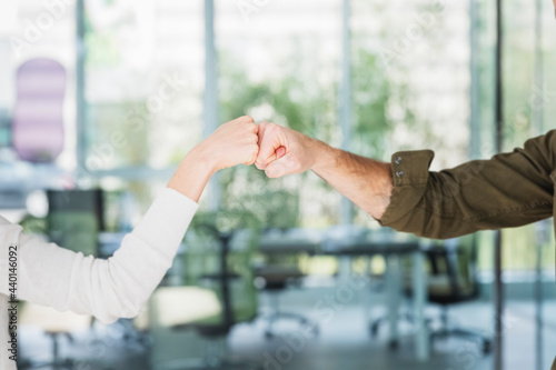 Male and female colleagues greeting with fist bumps in office photo