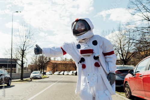 Male astronaut in space suit hailing ride during sunny day photo