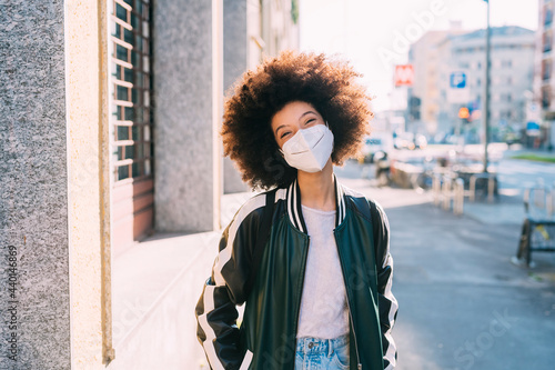 Curly hair woman with protective face mask standing on footpath photo