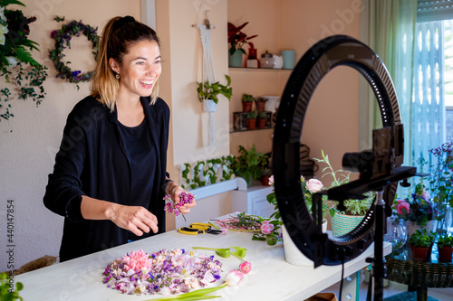 Female influencer teaching flower arrangement while vlogging at workshop photo