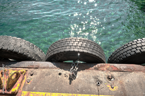 Old tyres hanging on port of karakoy istanbul bosphorus by means of metal chain for laying alongside something with turquoise color clear water