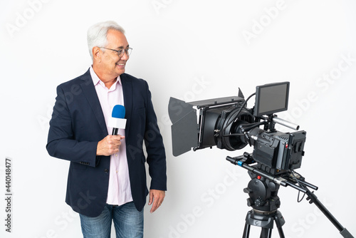 Reporter Middle age Brazilian man holding a microphone and reporting news isolated on white background looking side