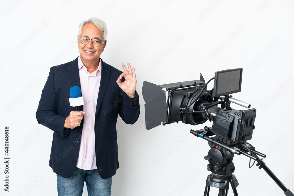 Reporter Middle age Brazilian man holding a microphone and reporting news isolated on white background showing ok sign with fingers