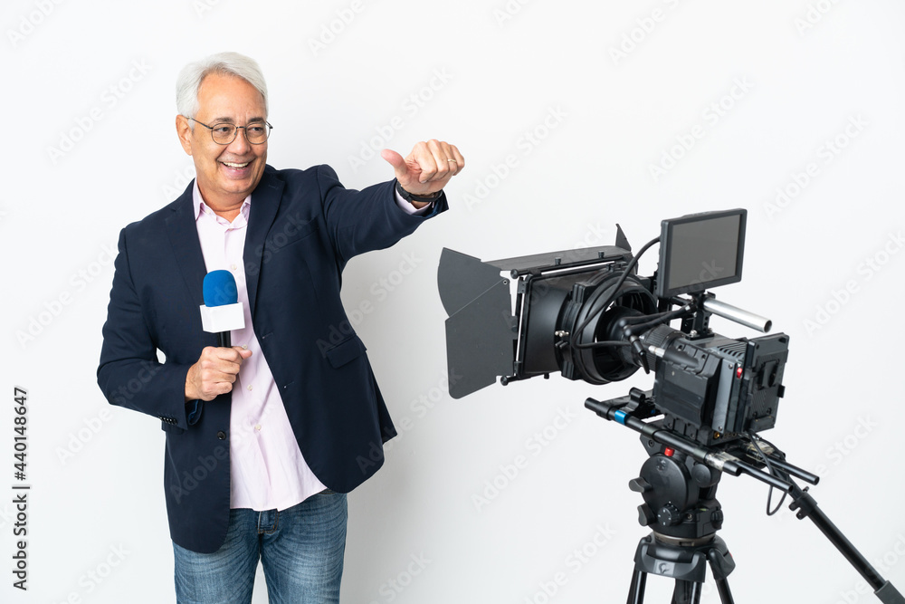 Reporter Middle age Brazilian man holding a microphone and reporting news isolated on white background giving a thumbs up gesture