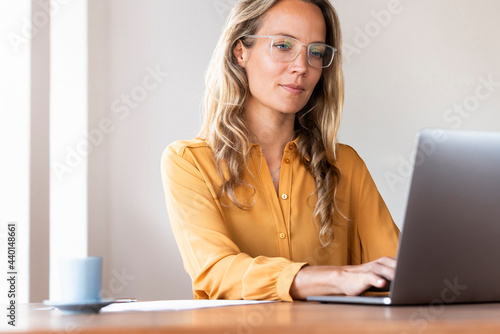 Female freelance worker using laptop at desk in home office