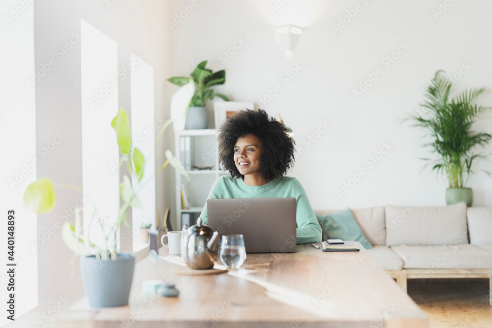 Smiling woman with laptop looking away at home Smiling woman with laptop looking away at home