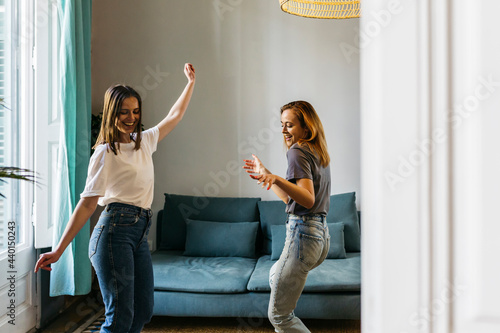 Happy girlfriends dancing in living room at home photo