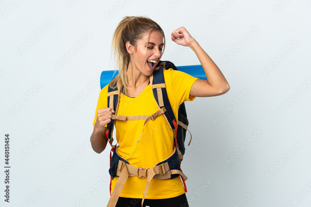 Young mountaineer woman with a big backpack isolated on white background celebrating a victory Young mountaineer woman with a big backpack isolated on white background celebrating a victory