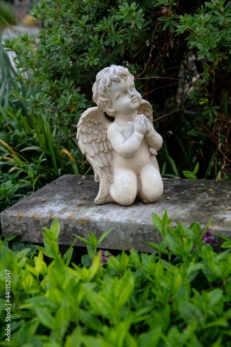 small kneeling white angel statue praying on a grave in an Austrian village