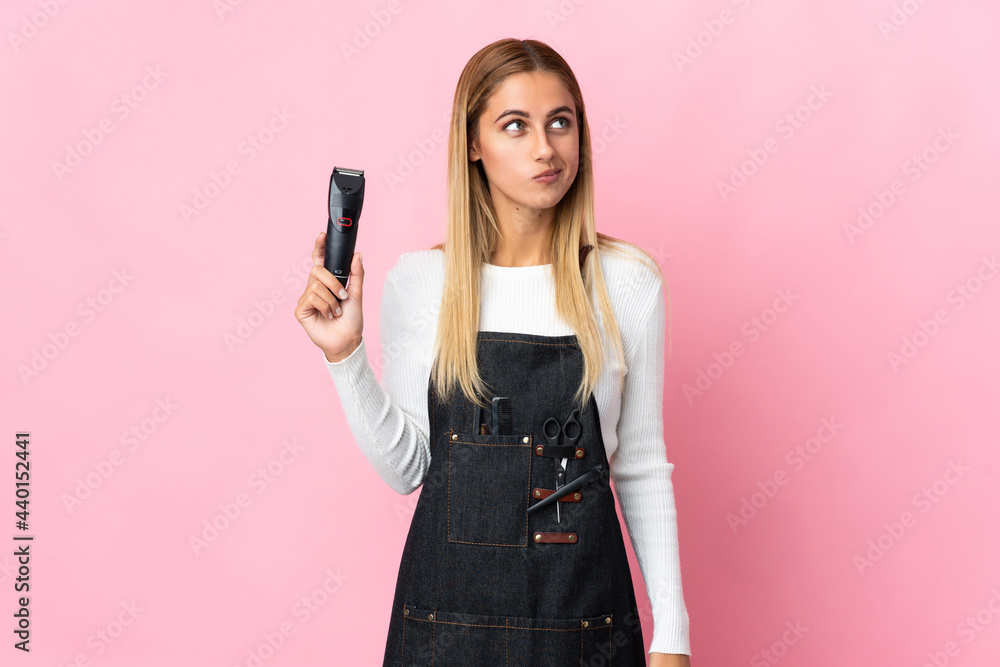 Young hairdresser woman isolated on pink background and looking up Young hairdresser woman isolated on pink background and looking up