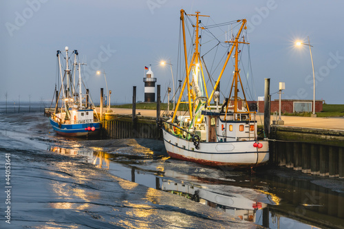 Germany, Lower Saxony, Wurster Nordseekuste, Fishing boats moored in beachside harbor at dusk photo