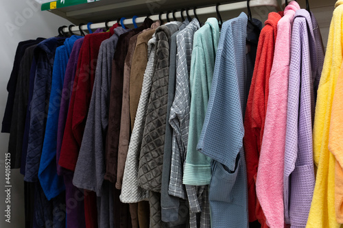 Lots of colorful women's and men's robes on hangers close-up