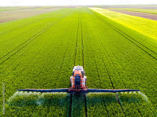 Tractor spraying fertilizer on agricultural field