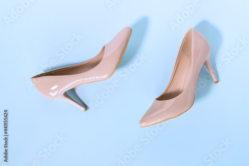 Classic beige women's shoes with medium heels on a blue background. The concept of sales and advertising. flatly. From above.