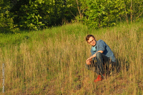 A young man sits in a field in the summer. High quality photo