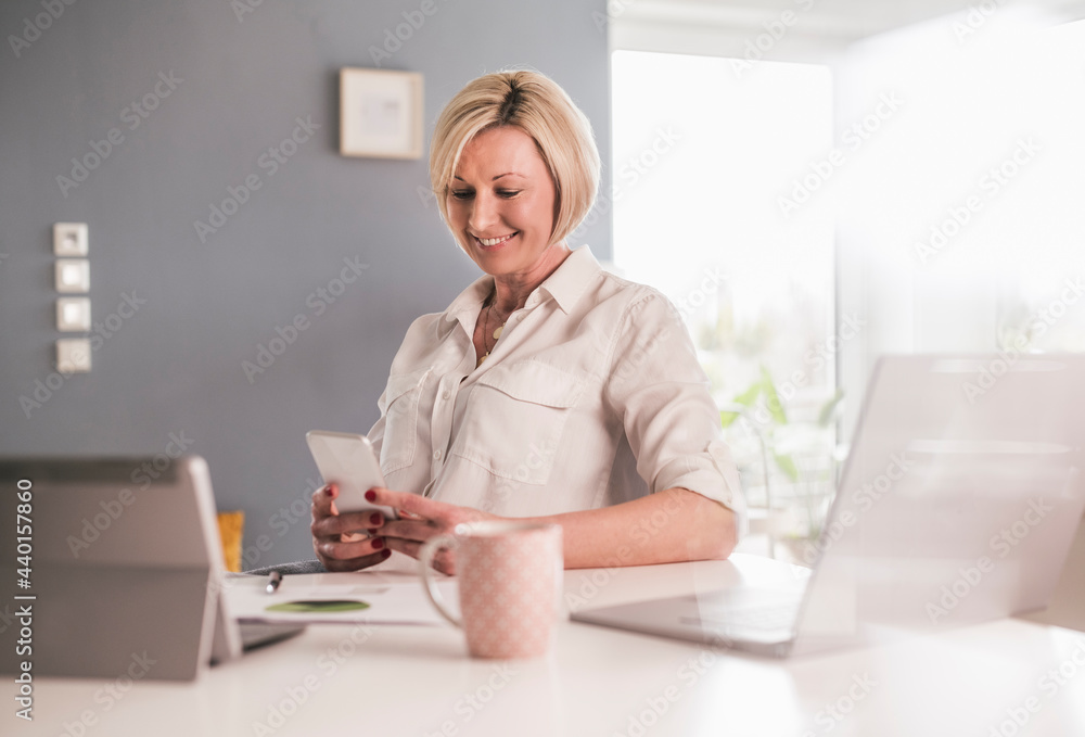 Smiling female professional working on smart phone in home office Smiling female professional working on smart phone in home office