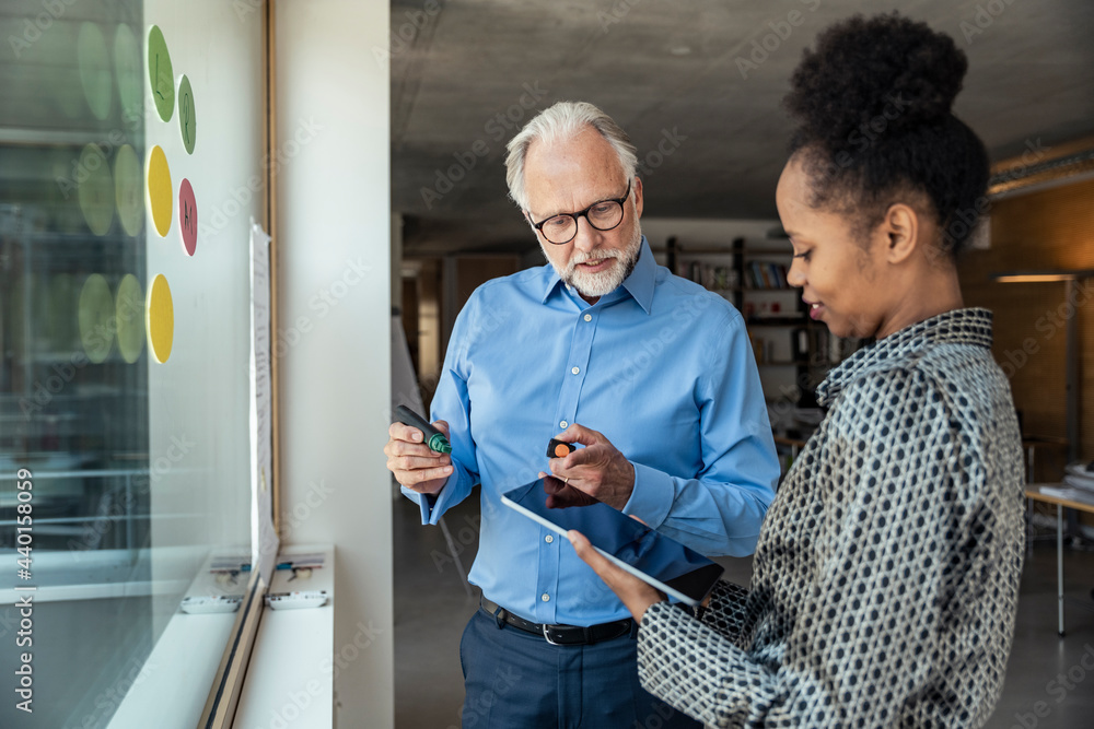 © Uwe Umstatter/Westend61 - Male and female professionals discussing over digital tablet at office