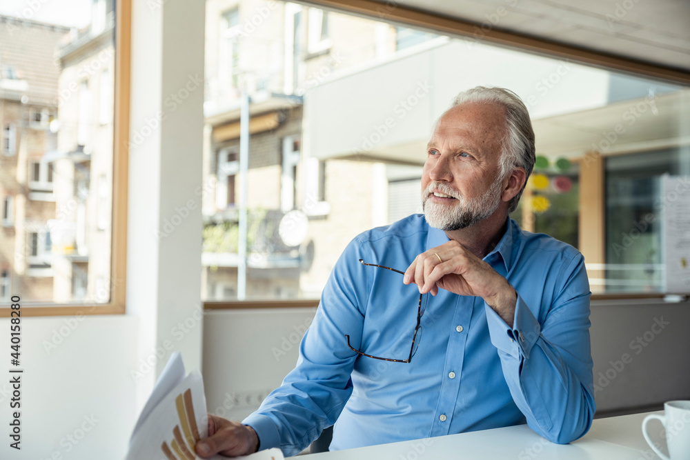 Businessman day dreaming while sitting at desk in office Businessman day dreaming while sitting at desk in office