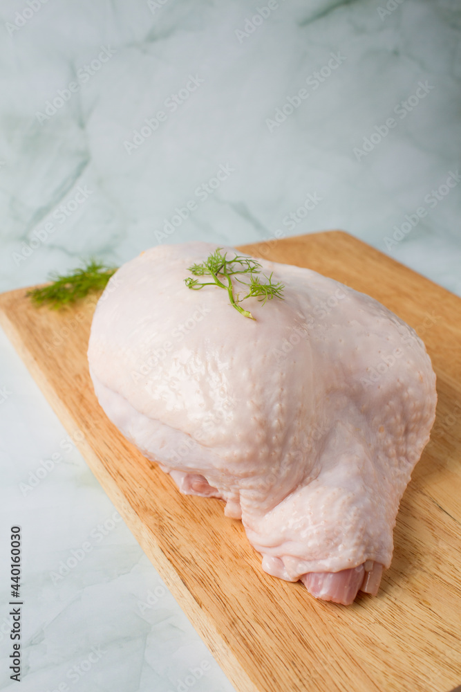 Raw chicken breast with skin and bones, over a wood table, flat lay Raw chicken breast with skin and bones, over a wood table, flat lay