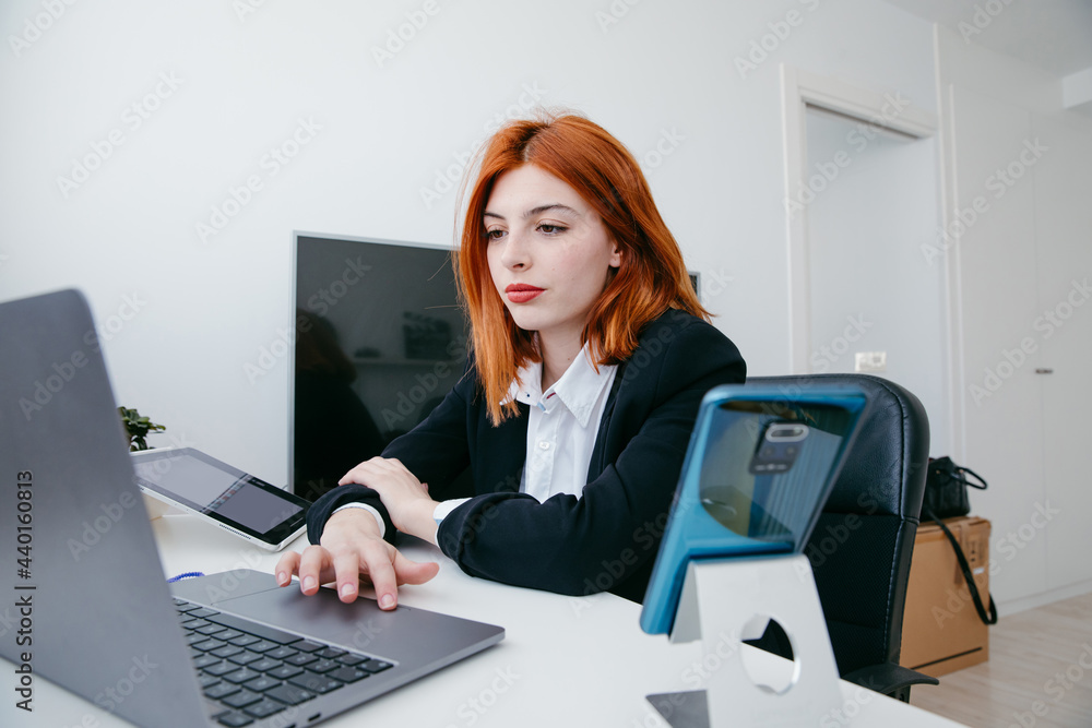 Businesswoman typing on laptop at table in house Businesswoman typing on laptop at table in house