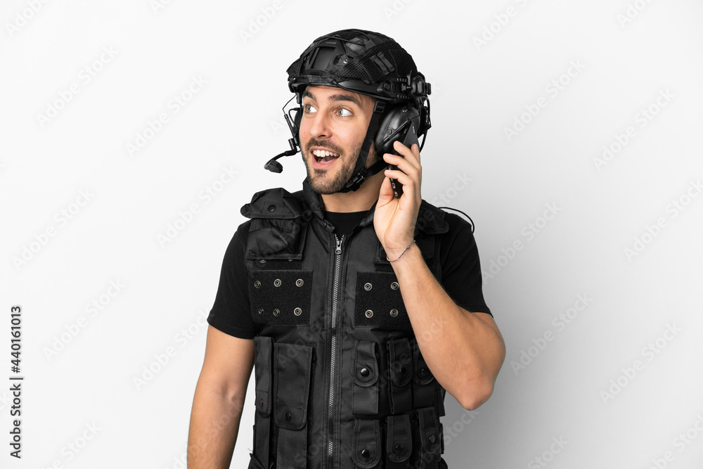 Young caucasian swat isolated on white background keeping a conversation with the mobile phone Young caucasian swat isolated on white background keeping a conversation with the mobile phone