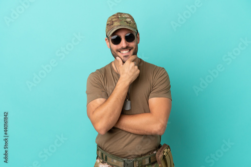 Military with dog tag over isolated on blue background with glasses and smiling