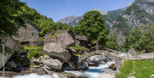The panoramic image of the ancient roman stone bridge at Puntid high over the Foroglio village in the Maggia valley, Tessin, Switzerland photo
