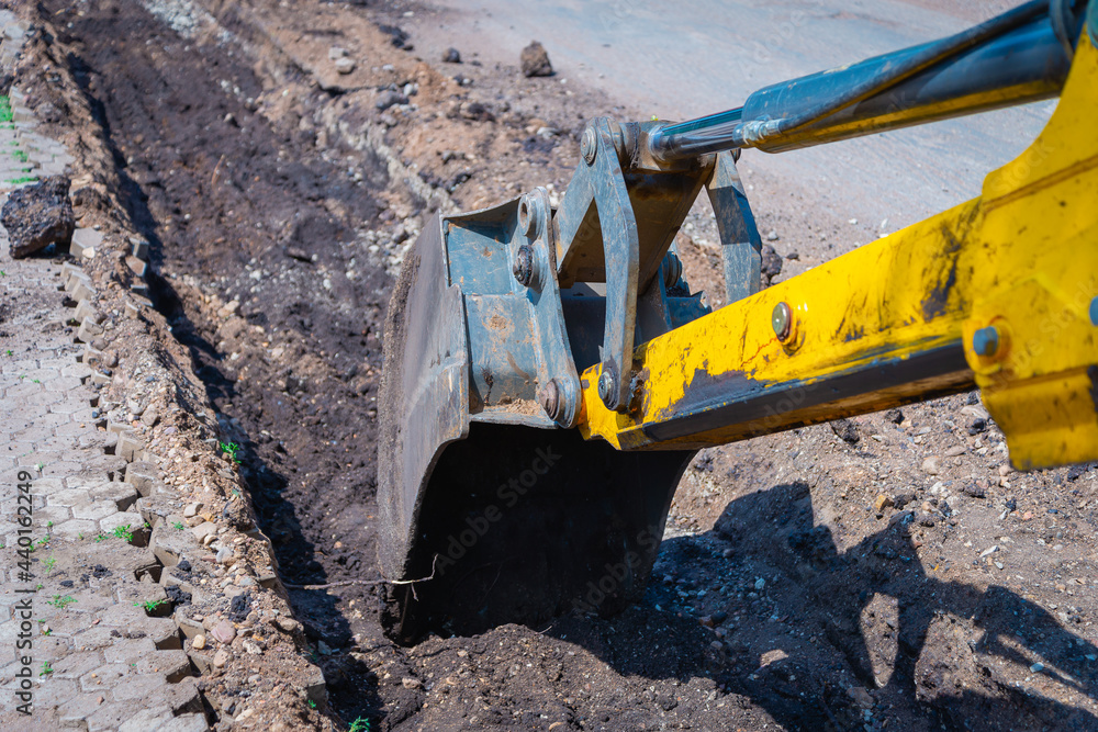 A tractor (excavator) prepares a trench for new curbs. A tractor (excavator) prepares a trench for new curbs.