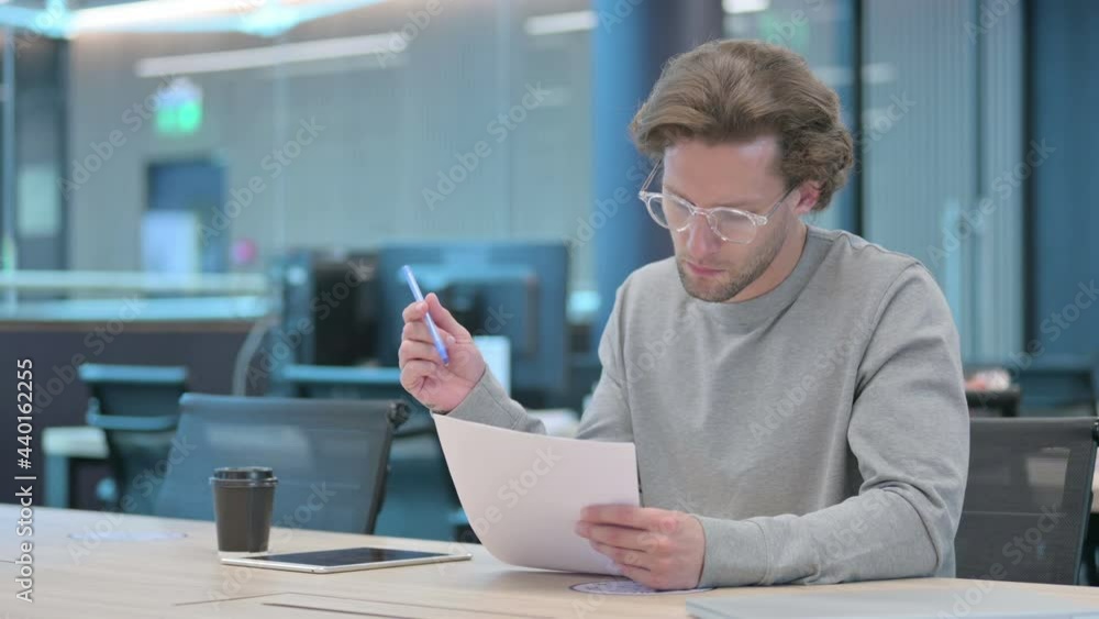 Young Businessman Reading Documents in Office Young Businessman Reading Documents in Office