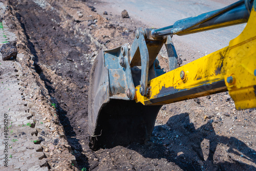 A tractor (excavator) prepares a trench for new curbs.