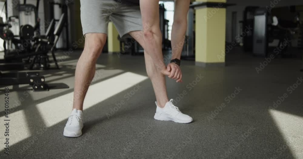 Young attractive muscular athlete works out in a modern gym. Strong man doing warm-up stretching exercises preparing for training. Active healthy lifestyle and wellbeing. Young attractive muscular athlete works out in a modern gym. Strong man doing warm-up stretching exercises preparing for training. Active healthy lifestyle and wellbeing.
