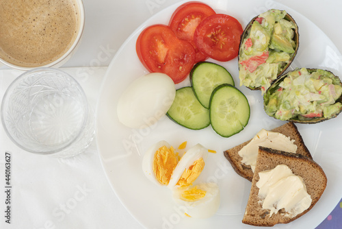 Breakfast on the bed Vegetables tomatoes and cucumbers salad of avocado and eggs. Serving white plate. Proper nutrition