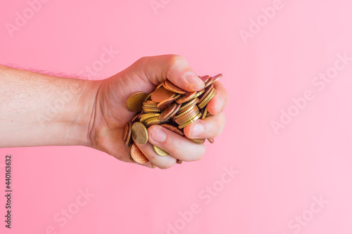 Fotografiet man's hand grabbing a pile of euro cent coins