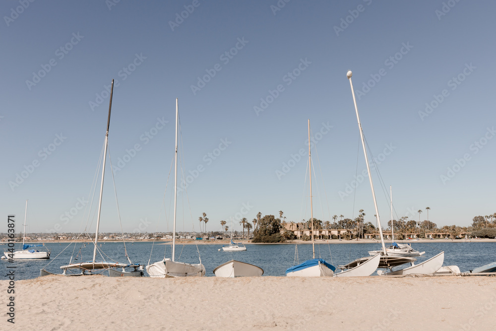 Horizontal Photo of 5 small sailboats pulled onto the beach at Mission Bay San Diego California