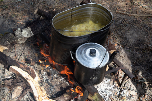 Cooking potatoes in a saucepan over an open fire. Lunch in nature. Tourist food.