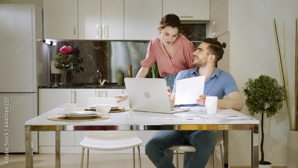 An adult man is sitting and working at home and talking with his wife An adult man is sitting and working at home and talking with his wife