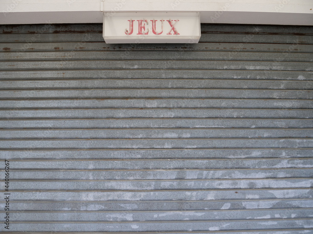 A closed metallic shutter, grey, France, June 2021.