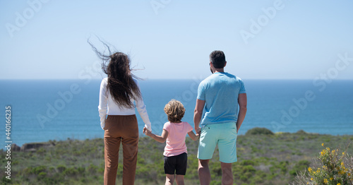 Back view of family on the beach. People having fun on summer vacation. Lifestyle family. Father, mother and child holding hands against blue sea. Holiday travel concept. Banner, copy cpase photo