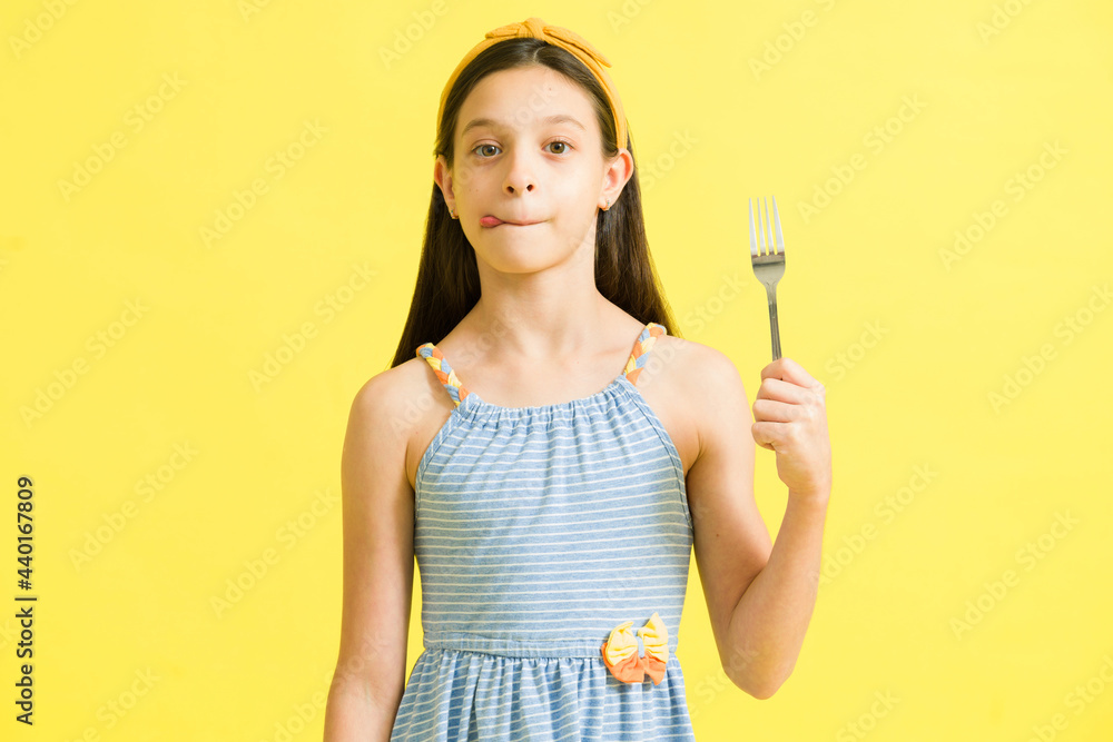 Little girl with cravings holding silverware Little girl with cravings holding silverware