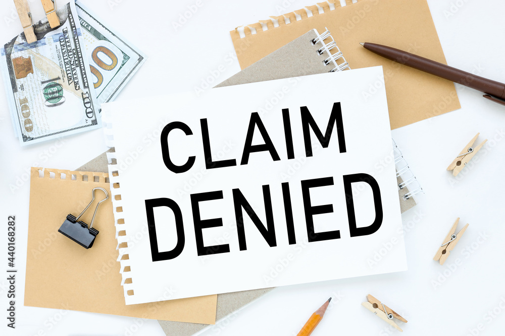 CLAIM DENIED. text on white notepad paper. on a white photo with torn paper CLAIM DENIED. text on white notepad paper. on a white photo with torn paper