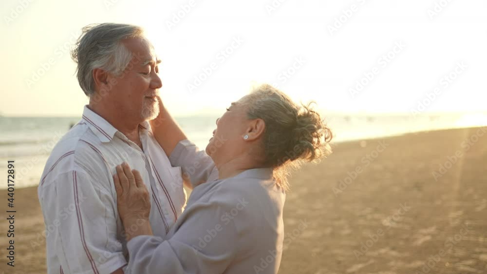 Happy Asian family senior couple holding hand and dancing on the beach together at summer sunset. Elderly retired husband and wife relax and enjoy romantic outdoor holiday vacation with happiness Happy Asian family senior couple holding hand and dancing on the beach together at summer sunset. Elderly retired husband and wife relax and enjoy romantic outdoor holiday vacation with happiness