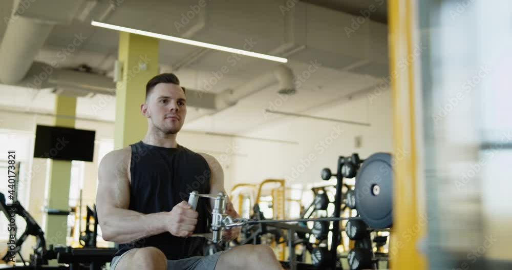 Young attractive muscular athlete works out in a modern gym. Strong fit man doing seated row machine exercises during training. Active healthy lifestyle and wellbeing. Young attractive muscular athlete works out in a modern gym. Strong fit man doing seated row machine exercises during training. Active healthy lifestyle and wellbeing.