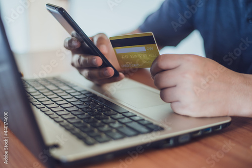 man holding credit card while using laptop for online shopping with selective focus on the credit card, online payment and financial concept.