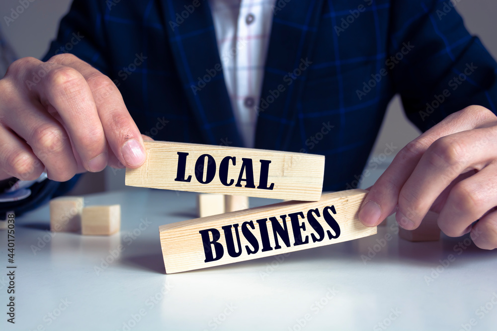 Obraz premium businessman holds wooden blocks with the inscription local business. small business development concept
