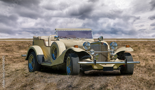 Spectacular view of a classic Excalibur automobile in a field on a cloudy sky background