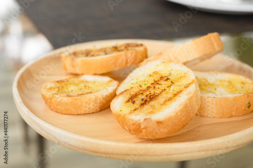 Selective focus shot of grilled garlic bread sliced with butter and spice looks delicious with yellow and brown color for snack or appetizer for yummy morning food or lunch served in restaurant.