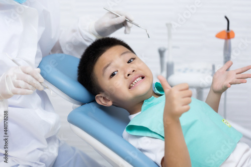 Dentist examining Asian little boy teeth in clinic. Calm and happy