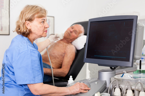 Pleasant female technician diagnosing male patient using modern ultrasound scanner in private clinic