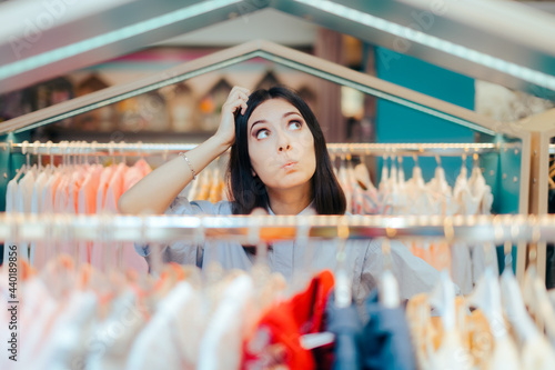 Obraz na płótnie Indecisive Female Customer Standing Among Clothing Racks