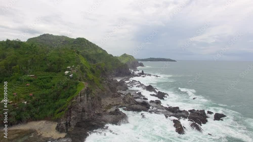 Aerial drone of Gunung Kidul beach, Yogyakarta, Indonesia. Calm waves near the mountain and cloudy weather. Aerial drone of Gunung Kidul beach, Yogyakarta, Indonesia. Calm waves near the mountain and cloudy weather.